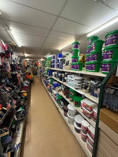 Narrow aisle in a hardware store with shelves stocked with various products.